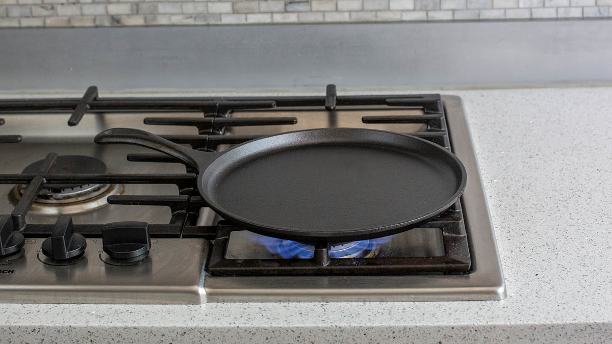 Lodge Classic black flat grill pan with a 26.7 cm diameter, suitable for outdoor or indoor grilling and searing.