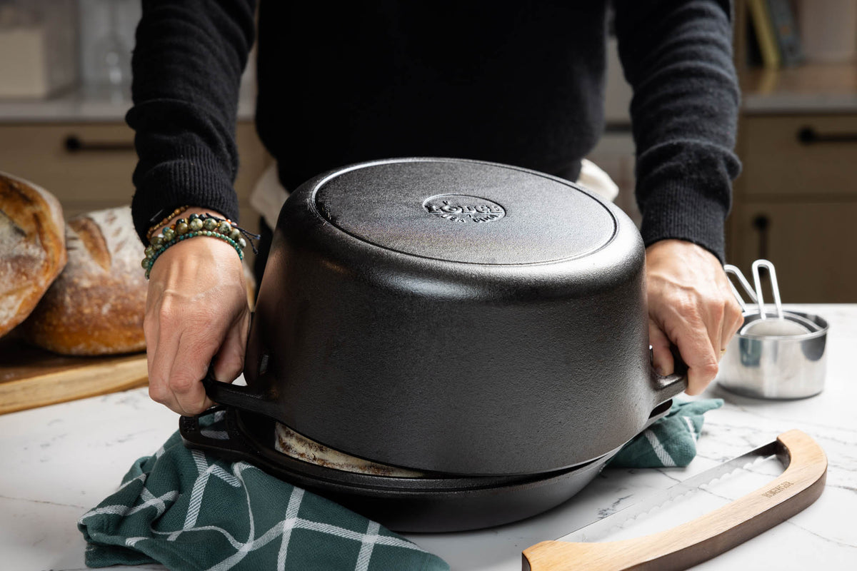 Lodge classic black cast iron Dutch oven with 12.3-liter capacity, shown with lid and sturdy handles for versatile cooking.