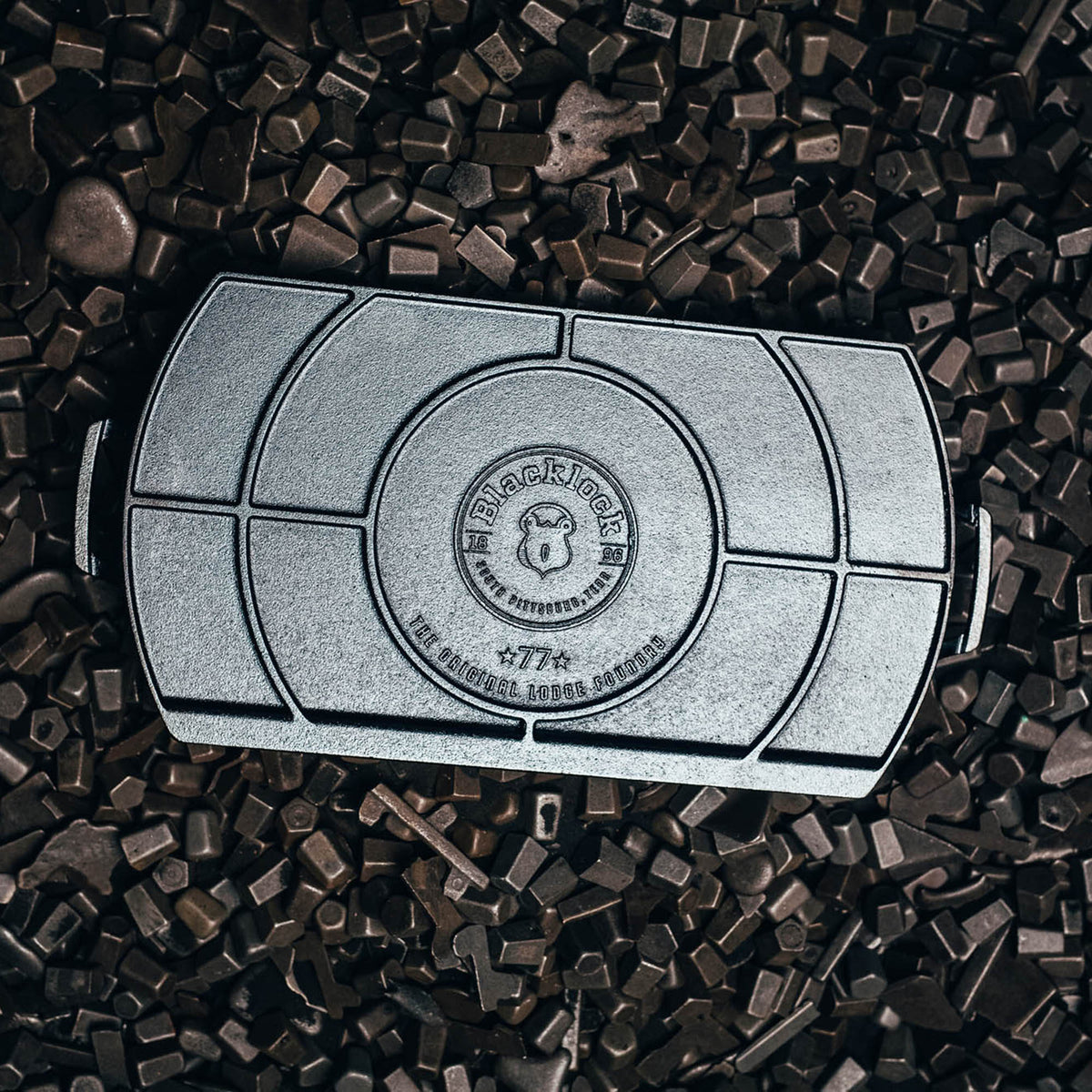 Lodge black cast iron grill plate, 51 cm, with a locking mechanism, suitable for outdoor grilling and cooking.