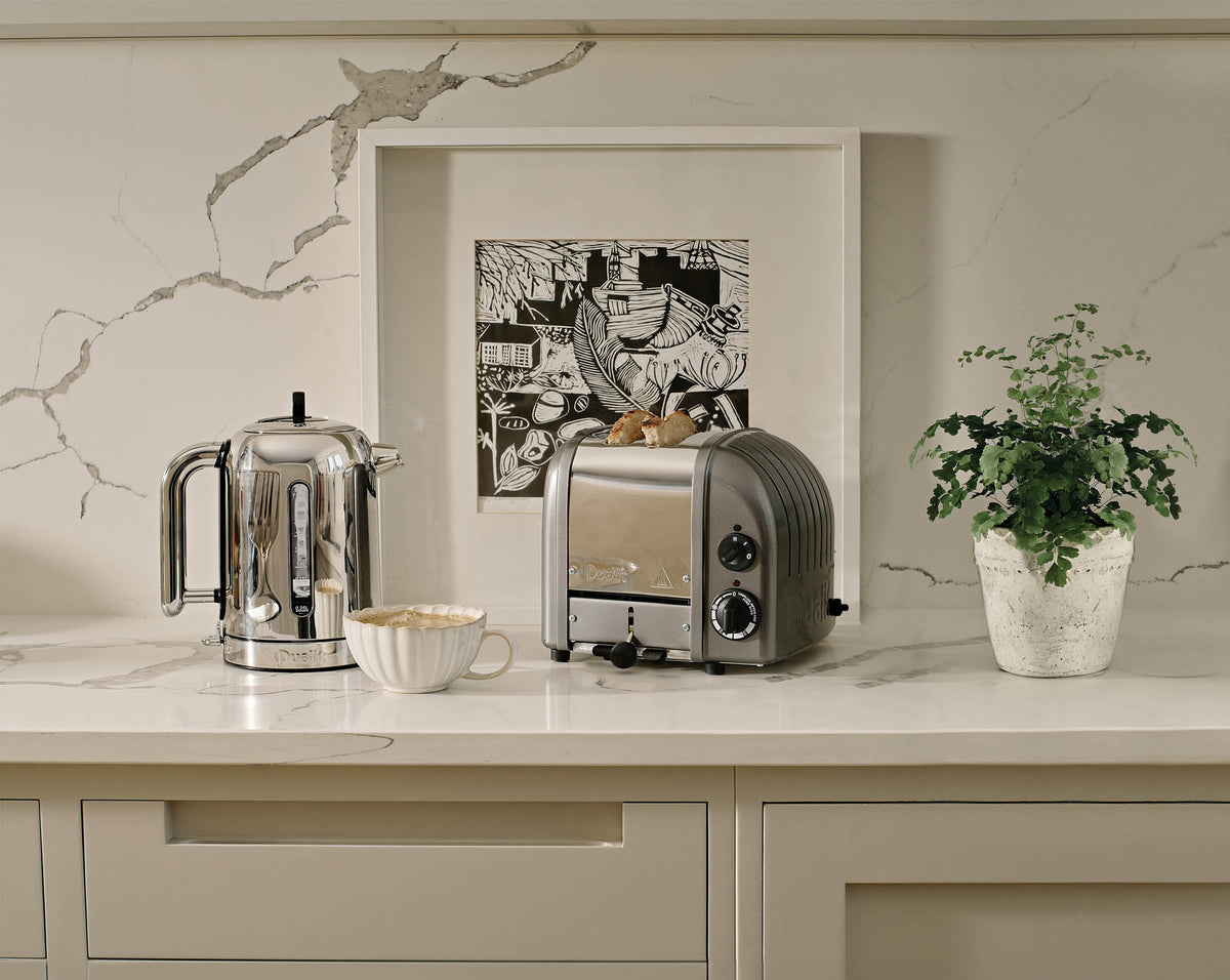 Dualit Newgen metallic gray 2-slice toaster with modern design and control buttons, shown in a kitchen setting.
