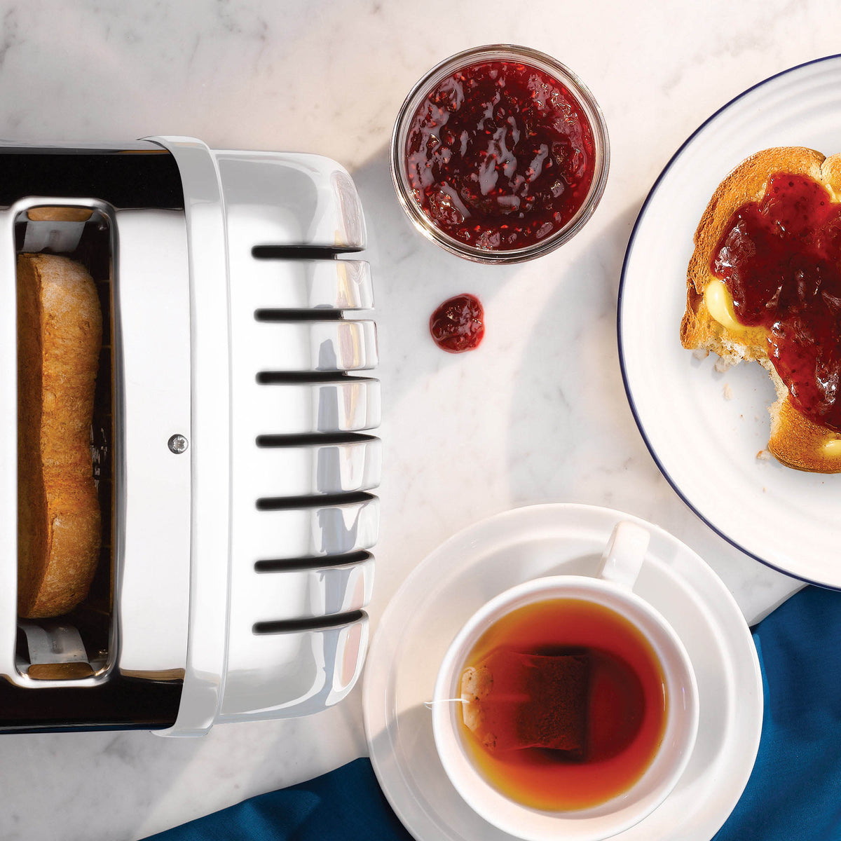 Dualit NewGen white 4-slice toaster with modern design and control knobs, ideal for toasting bread and bagels.