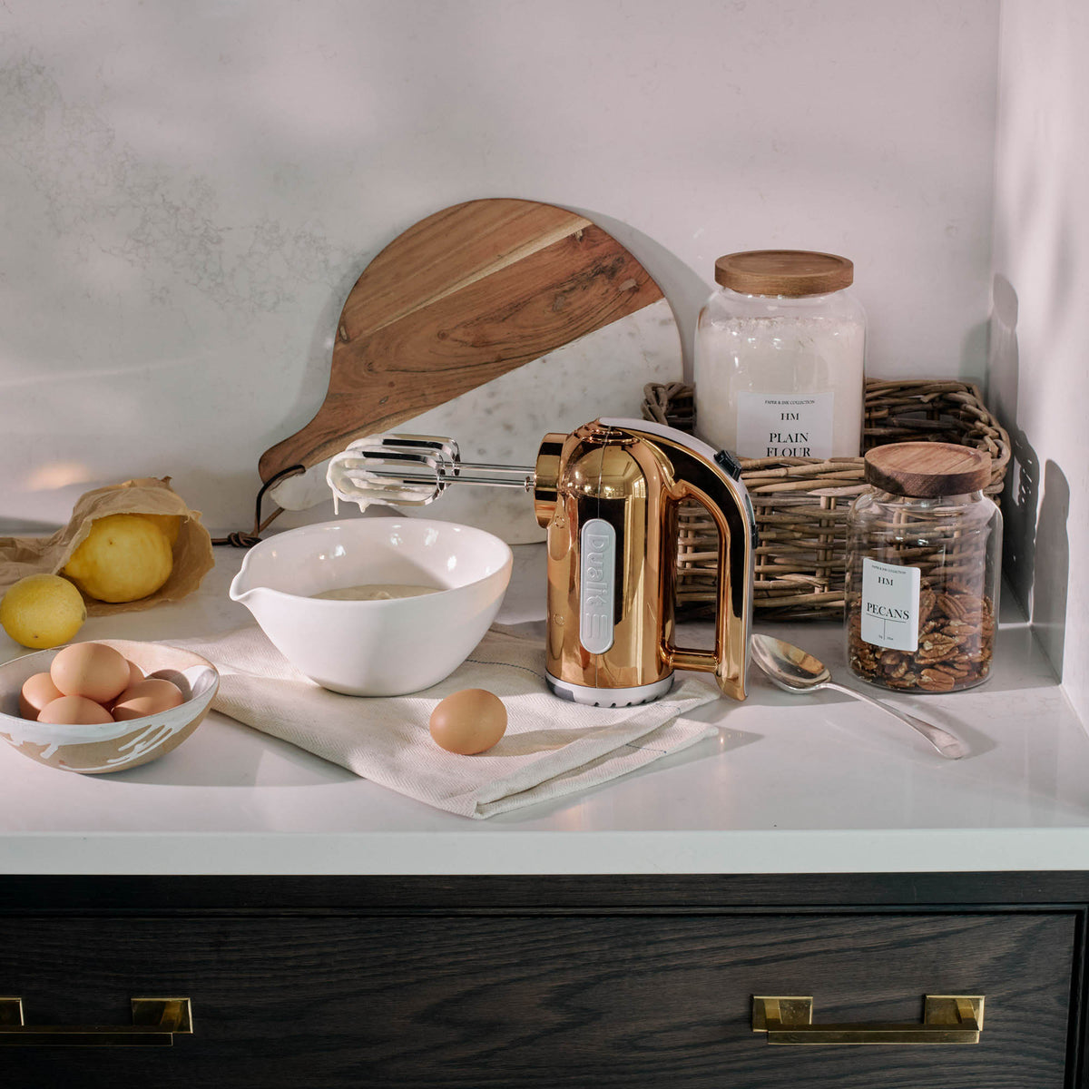Dualit Classic copper hand mixer with beaters and control buttons, compact and stylish kitchen appliance.