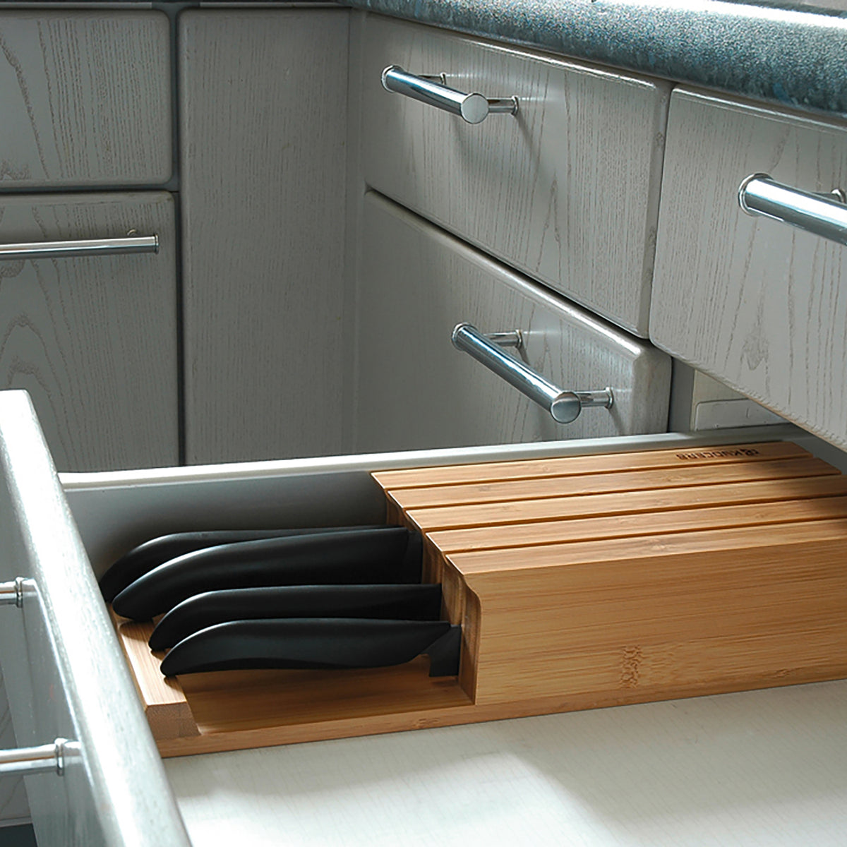 KYOCERA bamboo knife block with four Kyocera GEN ceramic knives, showcasing the sleek, natural wood design and knife handles.