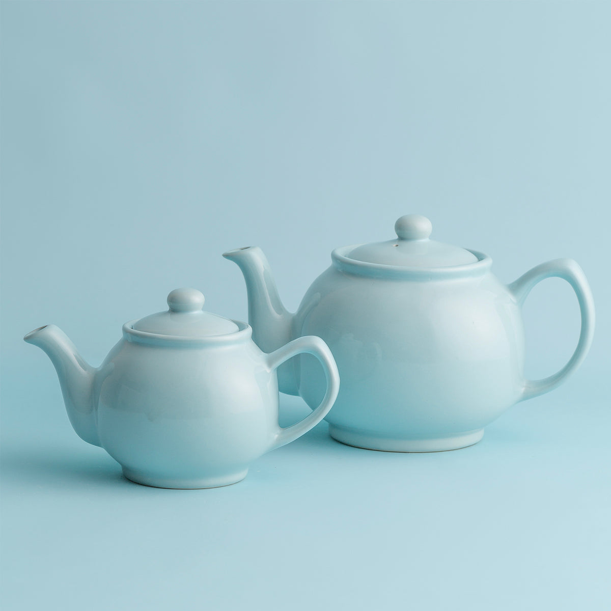 Blue P & K PRICE & KENSINGTON teapot with two matching teacups, ceramic tea set on a white background.
