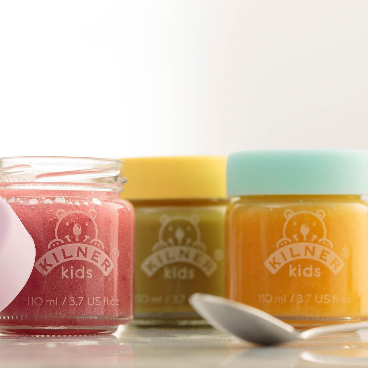Colorful KILNER baby jars with clear glass, designed for storing baby food or snacks in a vibrant, child-friendly style.