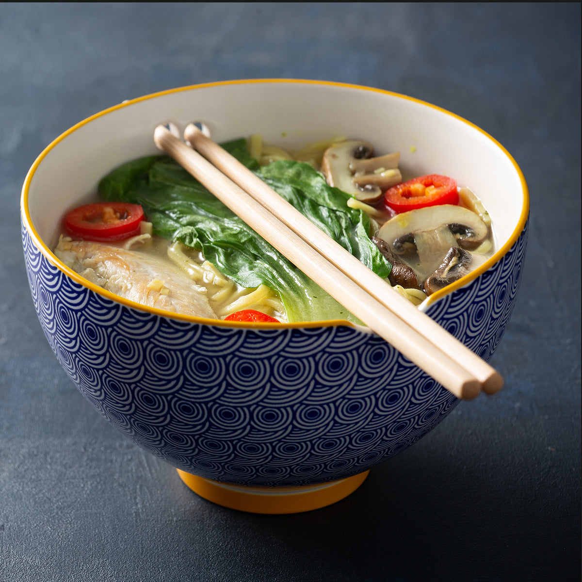 Blue TYPHOON Asian noodle bowl with chopsticks, round shape, and diameter for serving noodles and Asian cuisine.