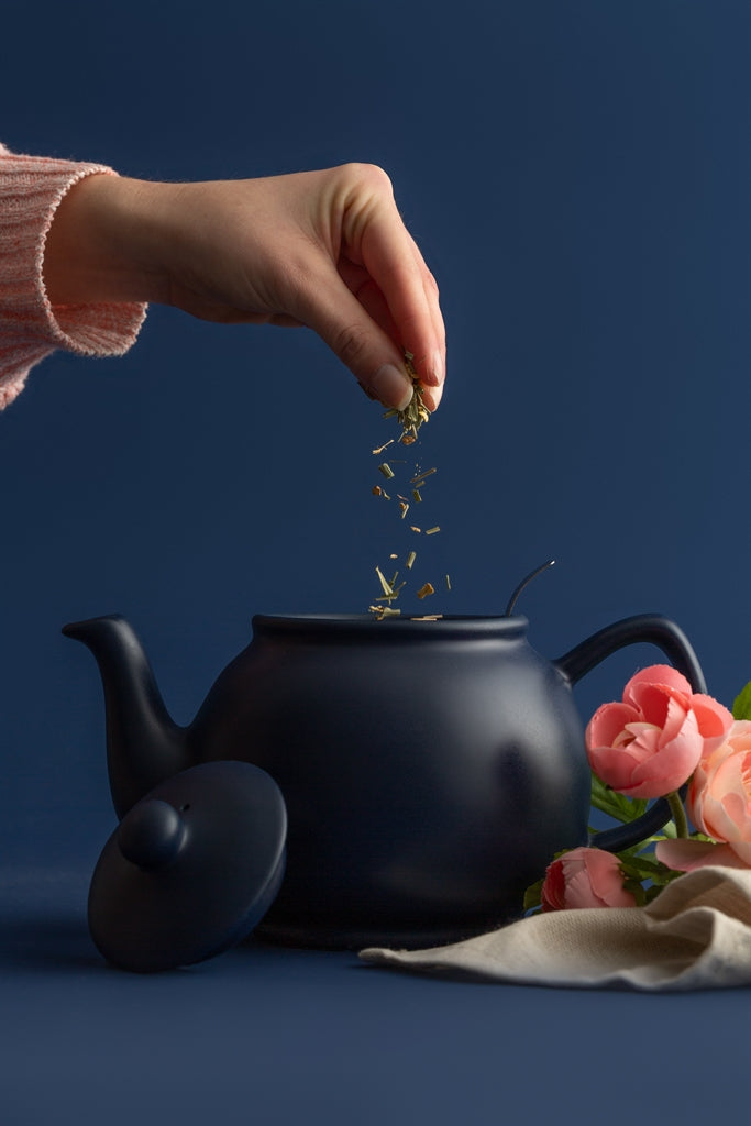 Blue P & K teapot with built-in infuser for brewing tea, shown with six matching cups.