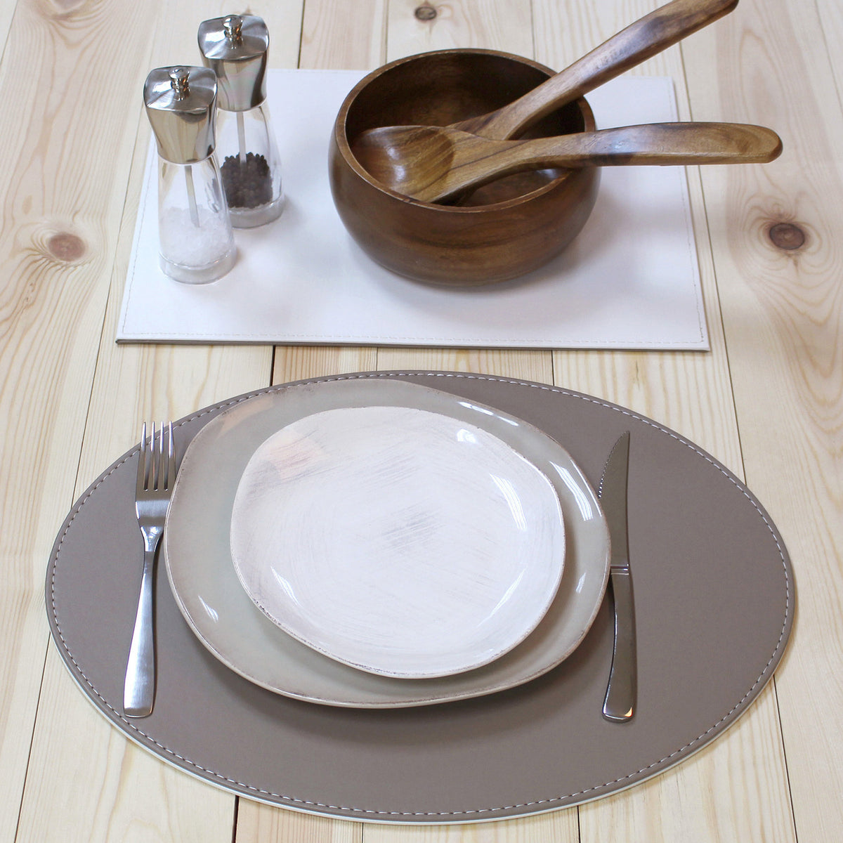 FREEFORM Platzset DUO in taupe and white, oval-shaped table setting with two woven placemats on a dining table.
