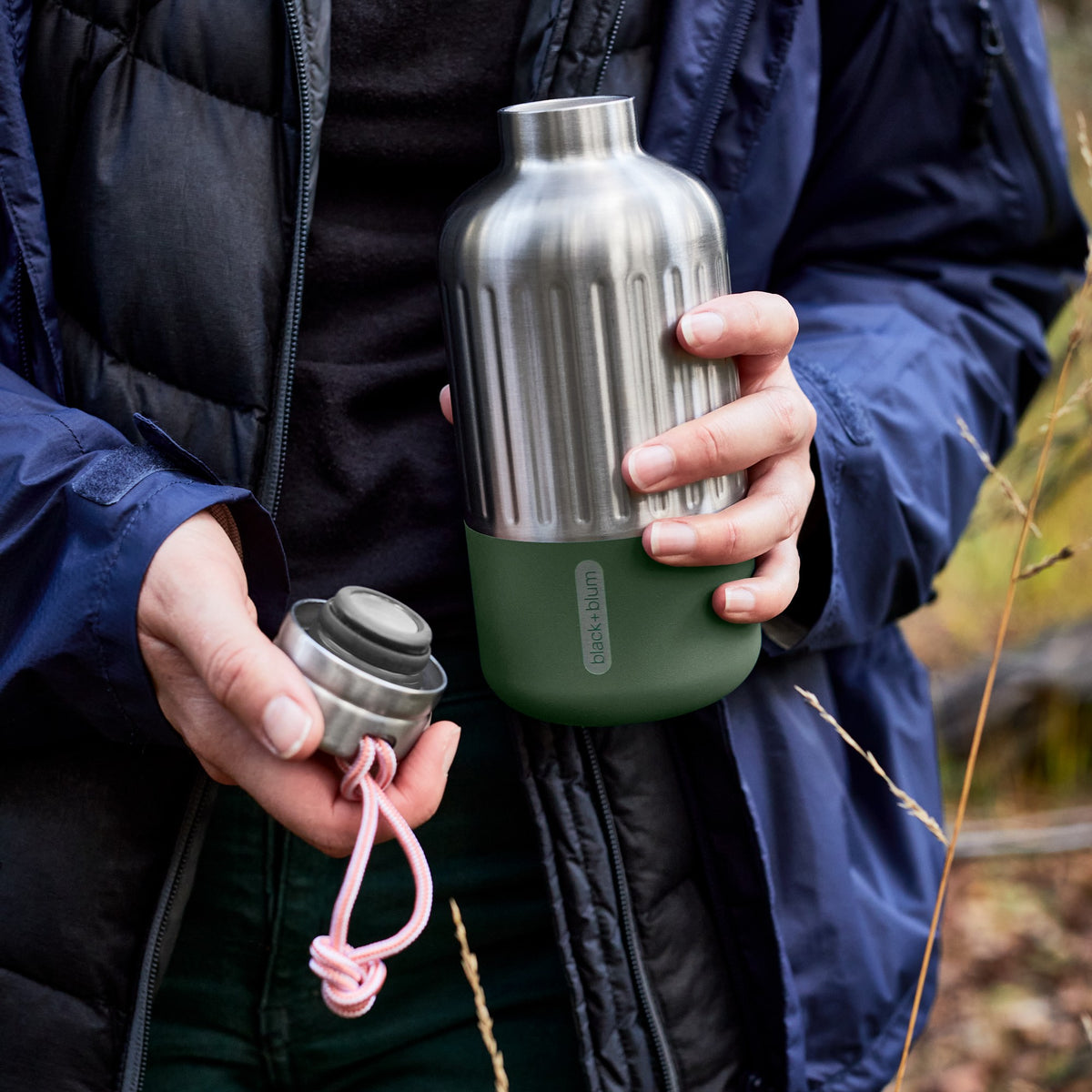 BLACK+BLUM Explorer isolierflasche in orange, small size, open with olive-green cap, designed for hiking and outdoor use.