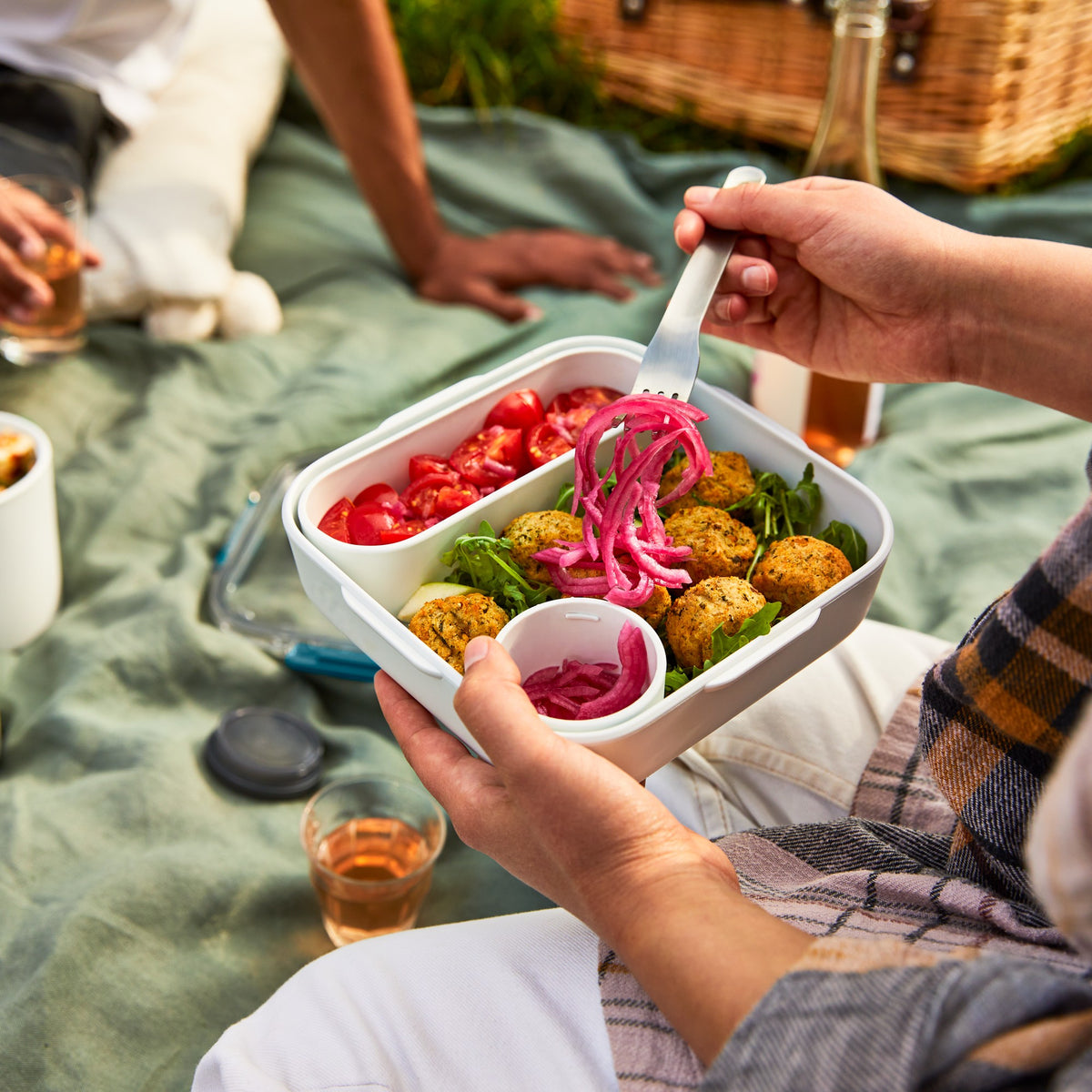 Black+Blum Original lunchbox with a black exterior, filled with falafel and salad, perfect for packed lunches and picnics.