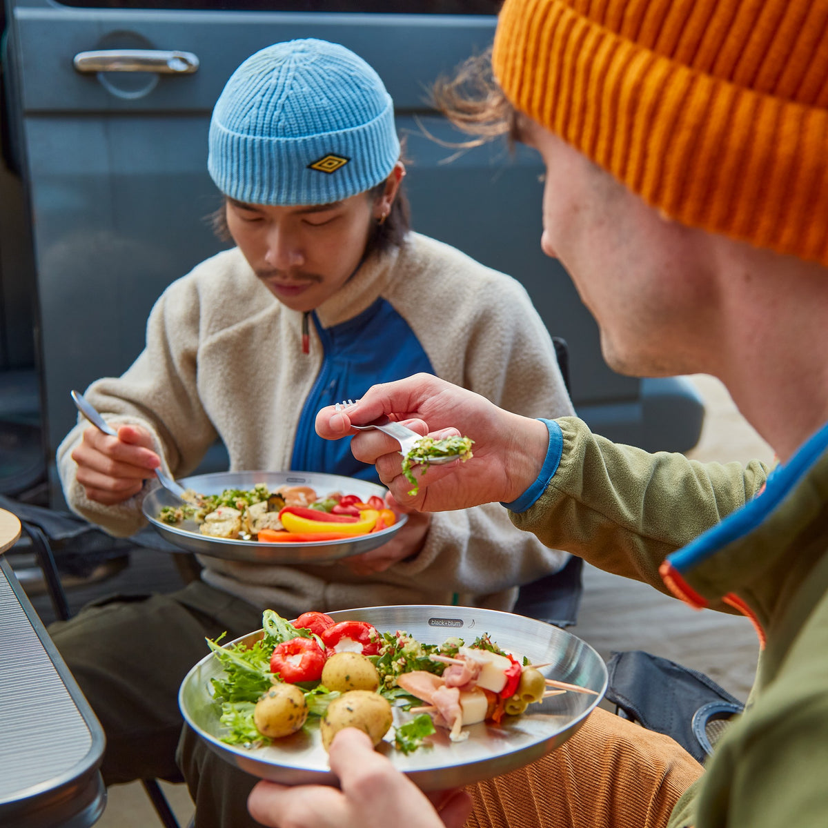 Set of four BLACK+BLUM stainless steel picnic plates, ideal for outdoor dining and beach picnics.