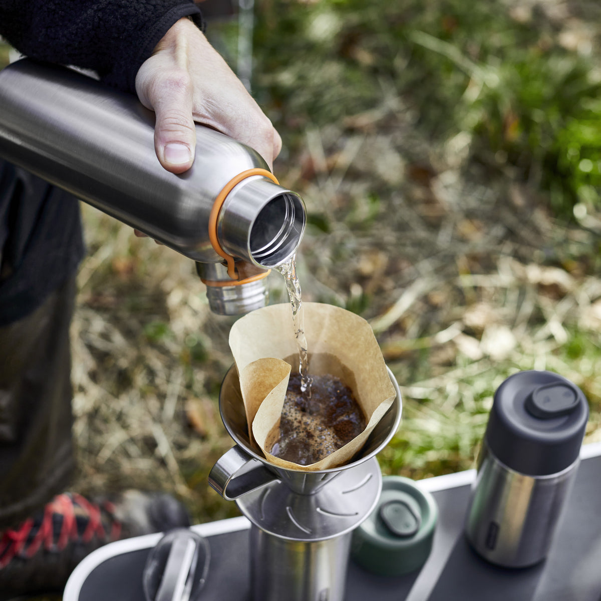 BLACK+BLUM insulated water bottle pouring water onto coffee, showcasing its thermal insulation and sleek design.