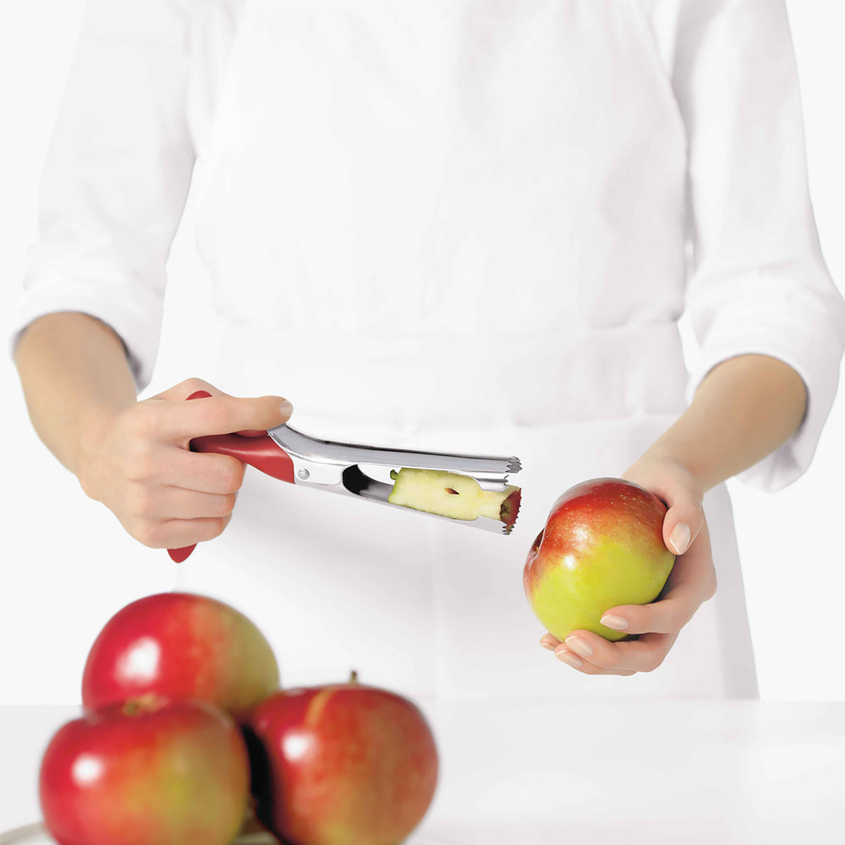 CUISIPRO red apple core remover, a handheld tool with a curved metal blade for coring apples.