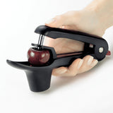 CUISIPRO cherry and olive pitter in black with ergonomic handle, designed for easy pitting of cherries and olives.