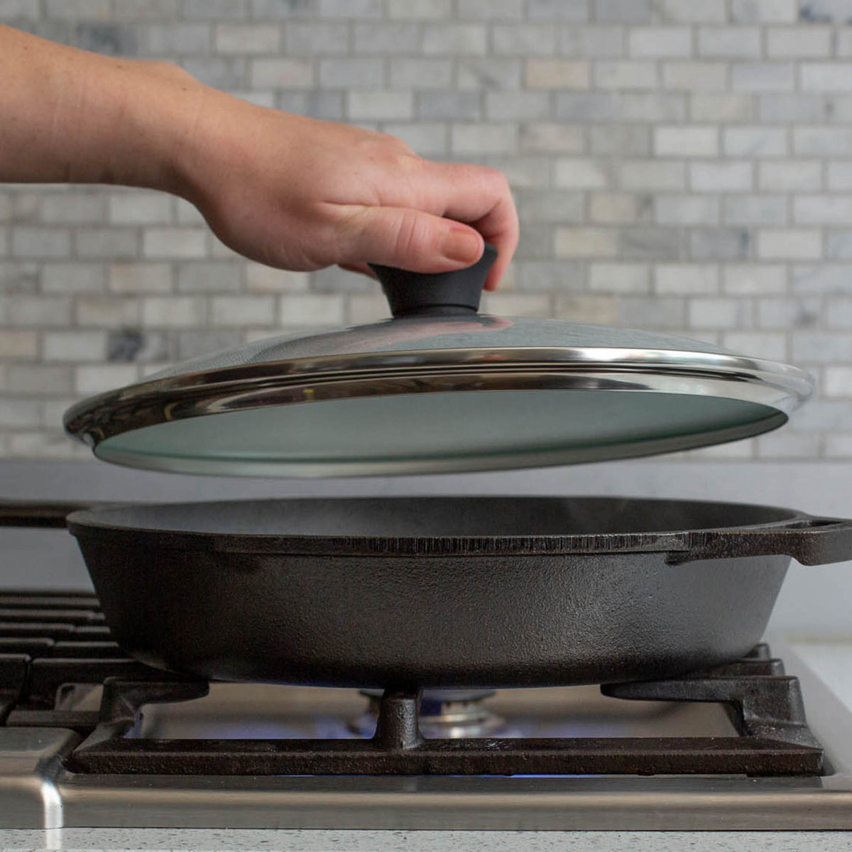 Black LODGE cookware lid with a sturdy handle, designed to fit compatible pots and pans, made of durable material.