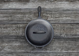 Black LODGE Classic lid for cookware, shown resting on a stove or cookware surface. Durable and heat-resistant kitchen accessory.