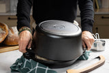 Lodge classic black cast iron Dutch oven with 12.3-liter capacity, shown with lid and sturdy handles for versatile cooking.