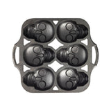 Lodge classic black cake pan with six skull-shaped molds, ideal for creative baking and themed cake designs.