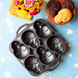 Lodge classic black cake pan with six skull-shaped molds, perfect for creative baking and themed desserts.