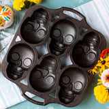 Lodge classic black cake pan with six skull-shaped molds for baking creative skull-themed desserts.