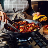 Lodge black cast iron 32cm chef wok with sturdy handle, ideal for stir-frying and versatile cooking.