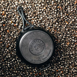 Lodge black 26cm cast iron skillet pan with black lock handle, shown from a top view.