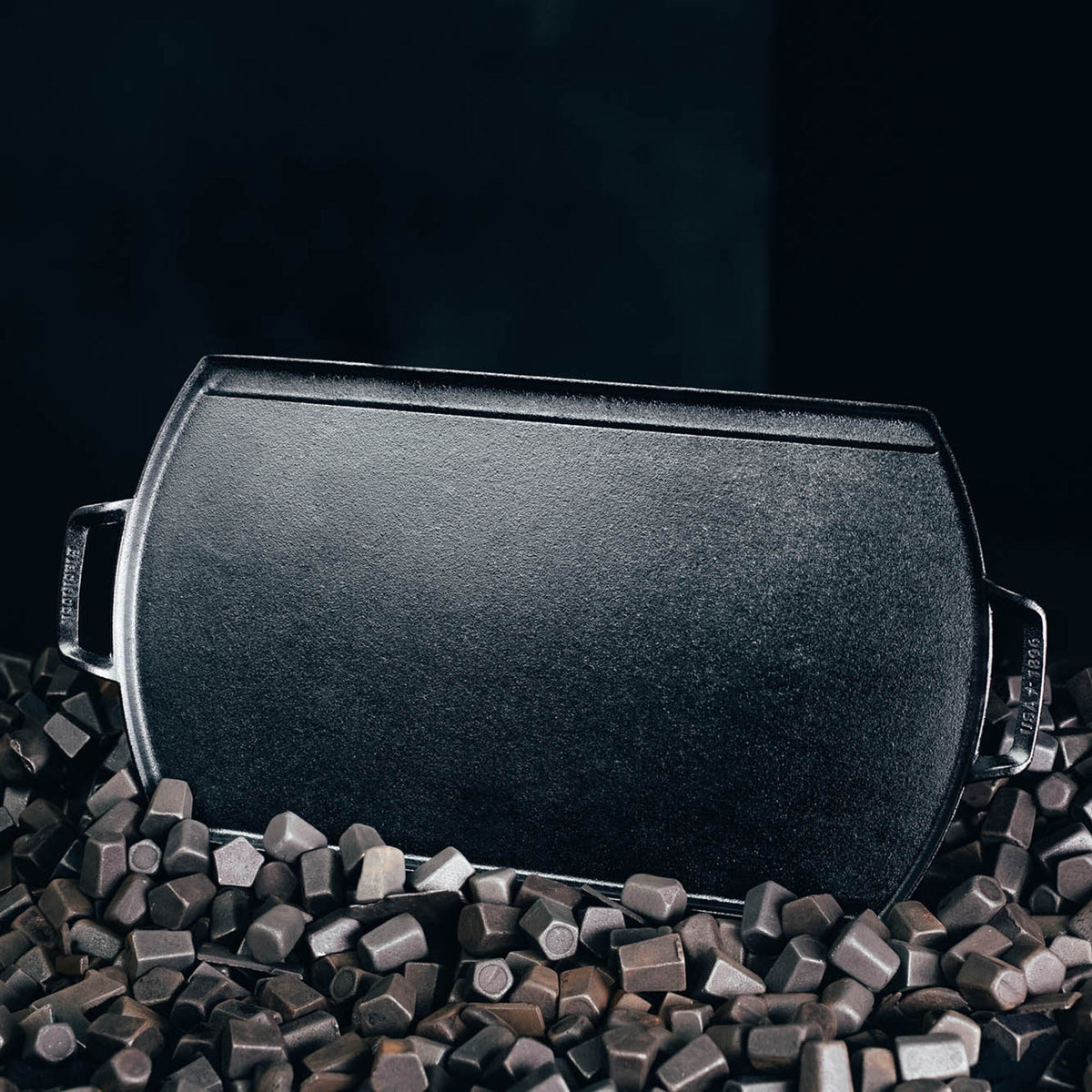 Lodge black cast iron grill plate, 51 cm size, with locking mechanism, suitable for outdoor grilling and cooking.