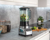 Dualit VORTECS polished stand mixer with stainless steel body and control dial, shown on a kitchen countertop.