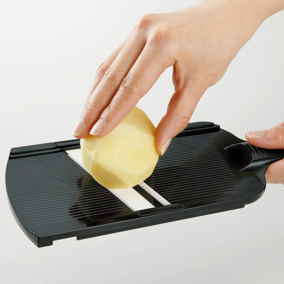 KYOCERA julienne vegetable peeler in black with sharp blade for precise julienne cuts, shown on a white background.