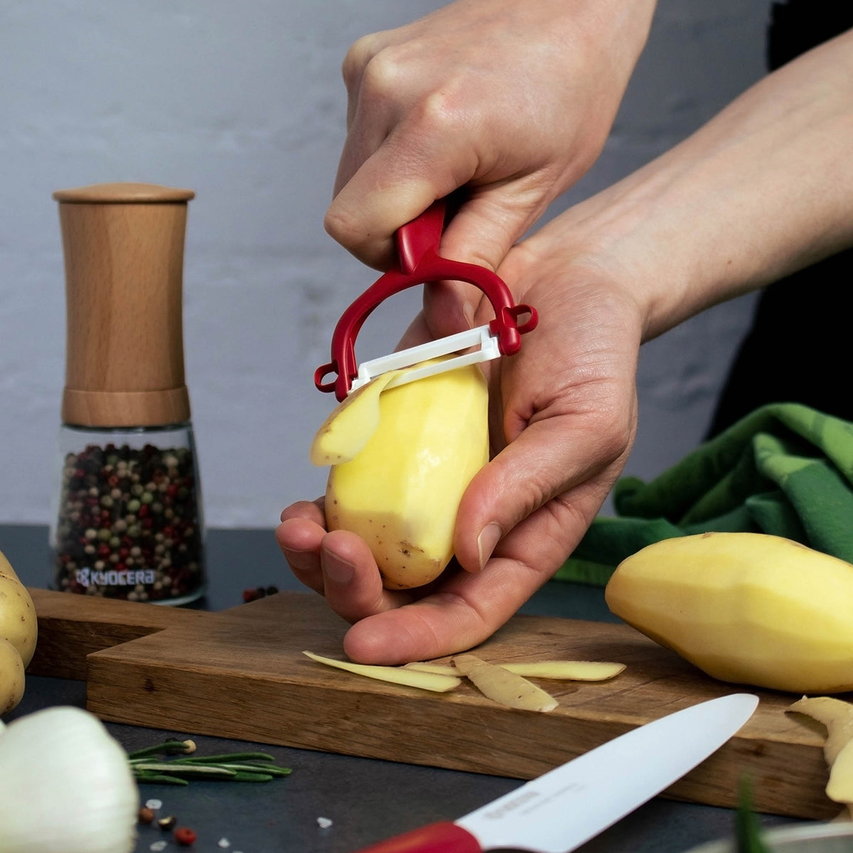 KYOCERA double-sided green peeler with sharp blades, ergonomic handle for peeling vegetables and fruits efficiently.