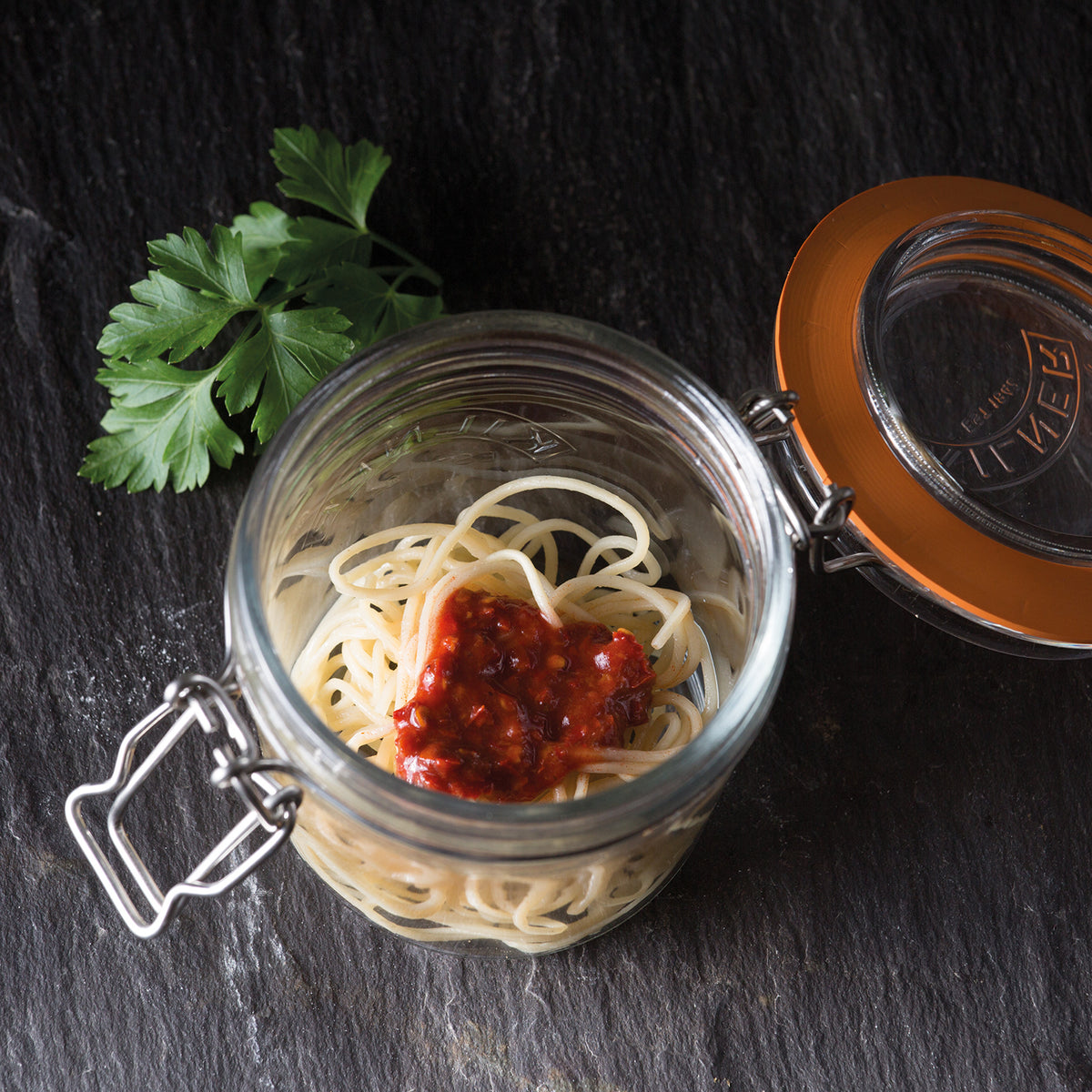 Clear Kilner Clip Round canning jar with metal clip lid for preserving fruits and jams, made from durable glass.