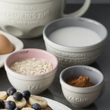 Set of four white Mason Cash measuring cups with clear markings, designed for accurate liquid and dry ingredient measurement.