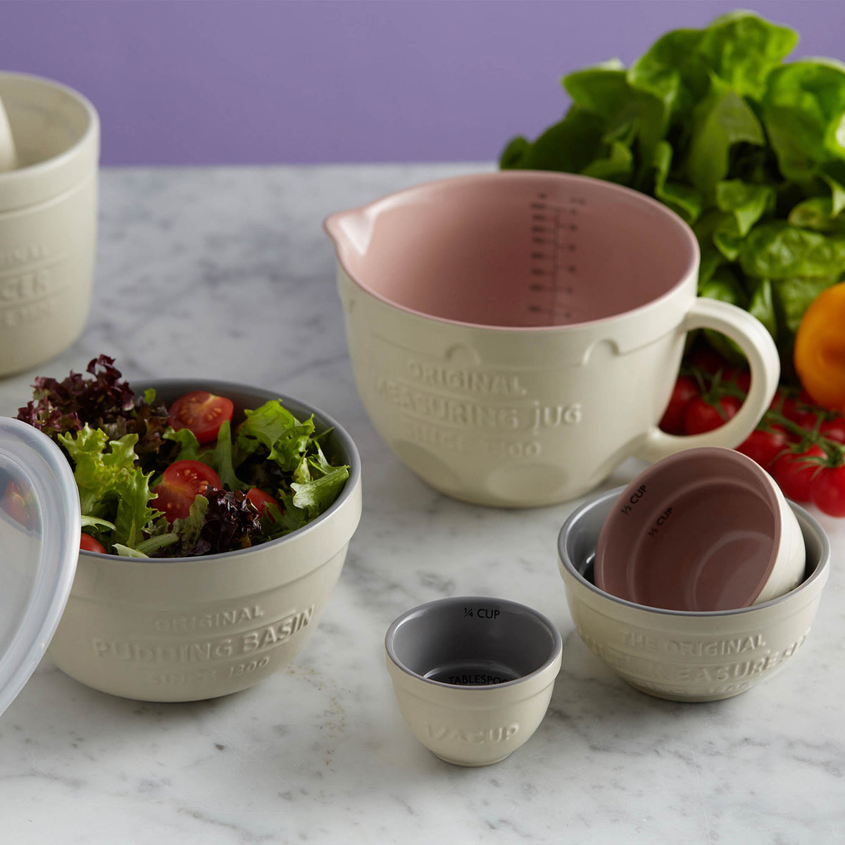 Set of four white Mason Cash measuring cups in a kitchen, displaying different sizes for accurate cooking and baking measurements.