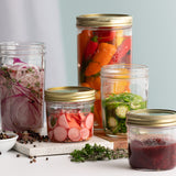 Clear Kilner wide-mouth canning jar with metal lid for preserving fruits and vegetables, made of durable glass.