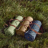 Green BLACK+BLUM picnic blanket, 2 x 1.4 meters, spread out on grass with a foldable design and soft fabric surface.