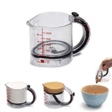 DREAMFARM messbecher measuring cup with clear markings, handle, and UPCUP label, used for precise liquid measurement in the kitchen.