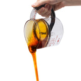 DREAMFARM Messbecher measuring cup with clear markings and a handle, used for precise liquid measurement in the kitchen.