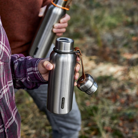 Black+Blum insulated water bottle in black, open to show stainless steel interior, ideal for hiking and outdoor use.