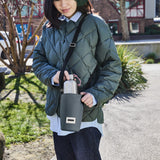Black+Blum bottle bag in slate, outdoor city scene, designed to carry and protect glass or plastic bottles.