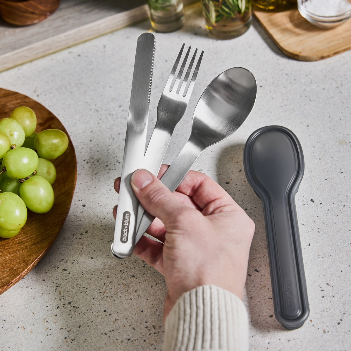 BLACK+BLUM stainless steel cutlery set in hand, designed for to-go lunch, compact and durable for portable eating.