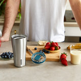 Black+Blum insulated travel tumbler with black exterior, designed for hot and cold beverages, shown on a summer shoot.