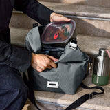 Black+Blum insulated lunchbag in slate color, large size with a sleek design, shown on stairs in a vertical view.