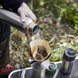 BLACK+BLUM insulated water bottle pouring water onto coffee, showcasing its thermal insulation and sleek design.